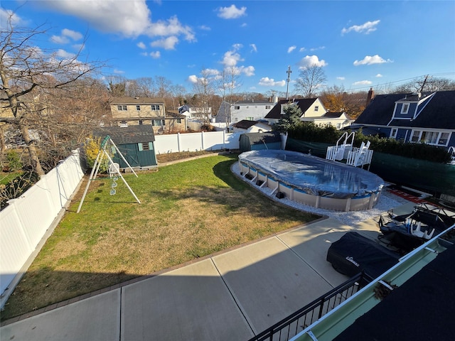 view of yard featuring a patio area, a covered pool, and a storage shed