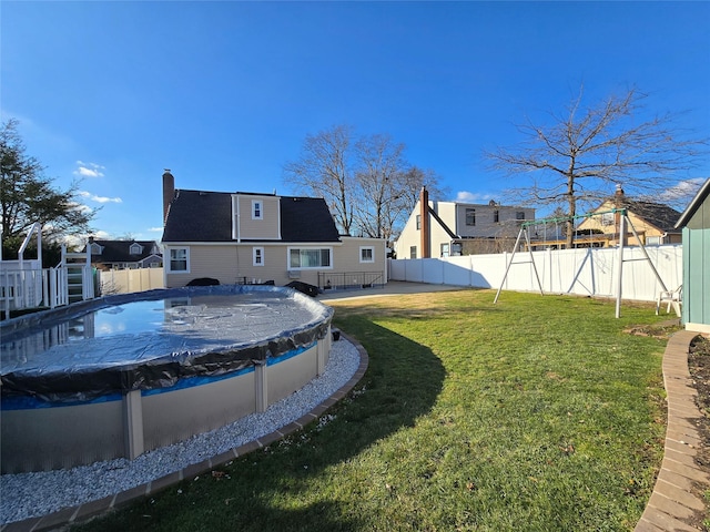 back of house with a yard and a covered pool