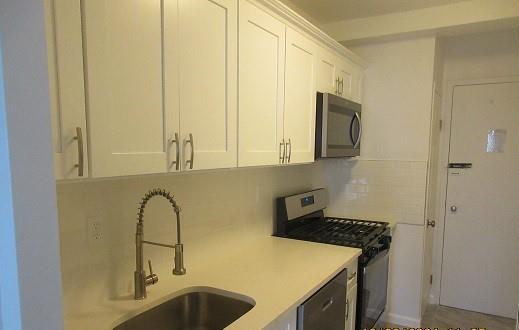 kitchen with white cabinets, appliances with stainless steel finishes, tasteful backsplash, and sink