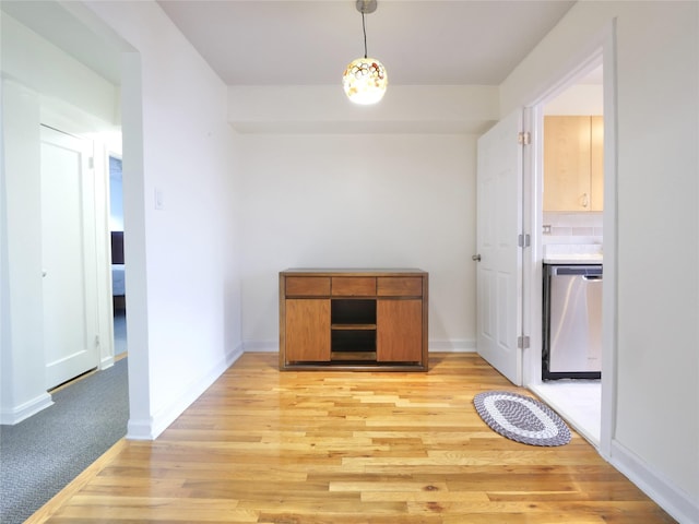 interior space with pendant lighting, dishwasher, light hardwood / wood-style floors, and backsplash