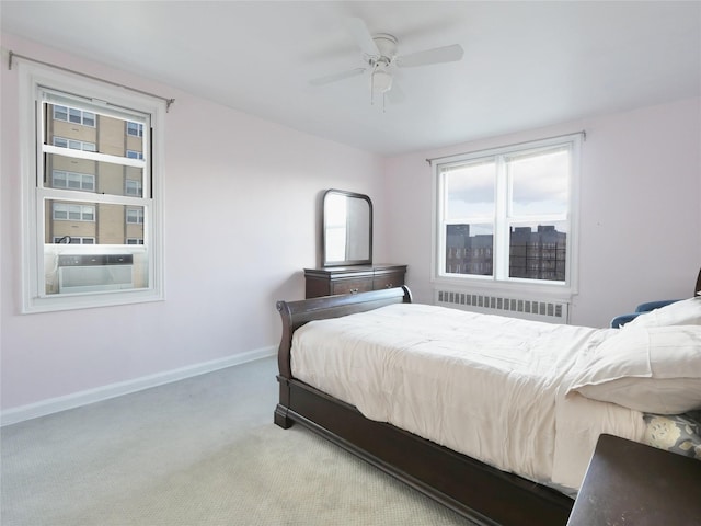 bedroom with ceiling fan, light colored carpet, and radiator