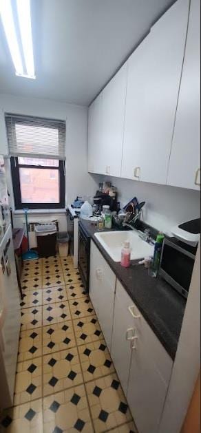 kitchen featuring light tile patterned floors, white cabinetry, and sink