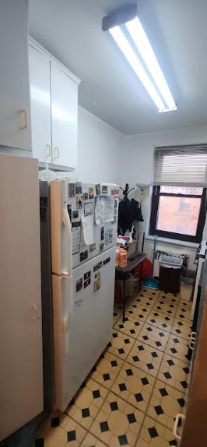 kitchen featuring tile patterned floors, stainless steel fridge, and white cabinets