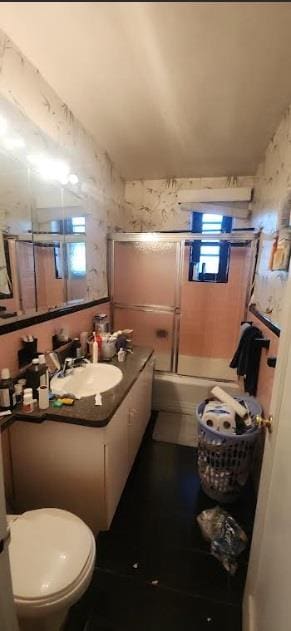 full bathroom featuring vanity, toilet, and shower / bath combination with glass door