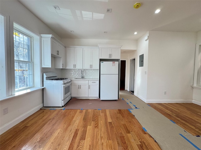 kitchen featuring white appliances, light hardwood / wood-style floors, white cabinetry, and a wealth of natural light