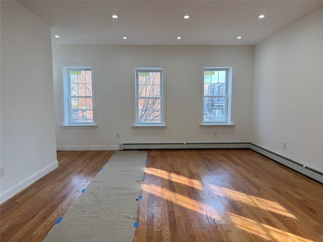 empty room with a baseboard heating unit and hardwood / wood-style flooring