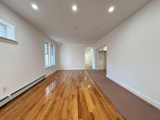 empty room with light hardwood / wood-style flooring and a baseboard heating unit