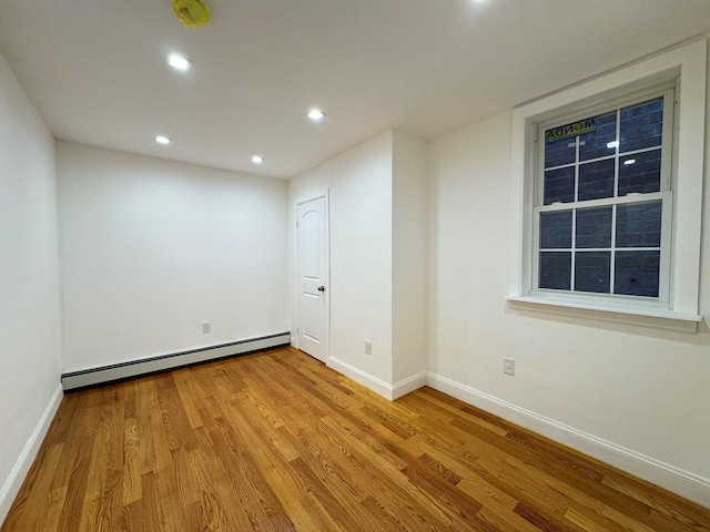 spare room featuring light wood-type flooring and a baseboard heating unit