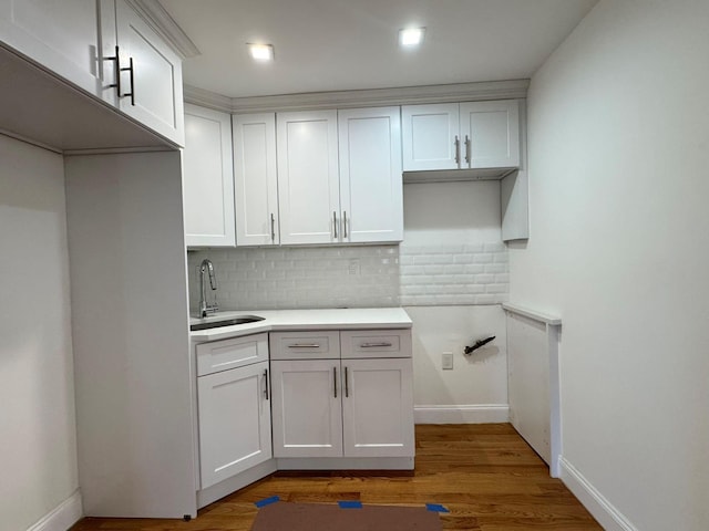 kitchen with hardwood / wood-style flooring, decorative backsplash, white cabinetry, and sink