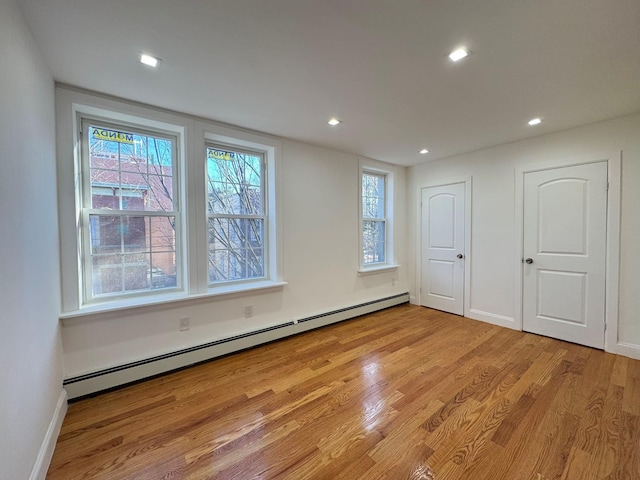 empty room with a baseboard radiator and light hardwood / wood-style flooring