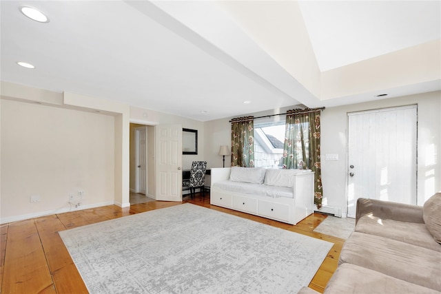 living room with a baseboard heating unit, light hardwood / wood-style floors, and lofted ceiling