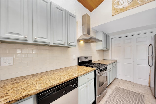 kitchen with vaulted ceiling, wall chimney exhaust hood, decorative backsplash, light stone counters, and stainless steel appliances