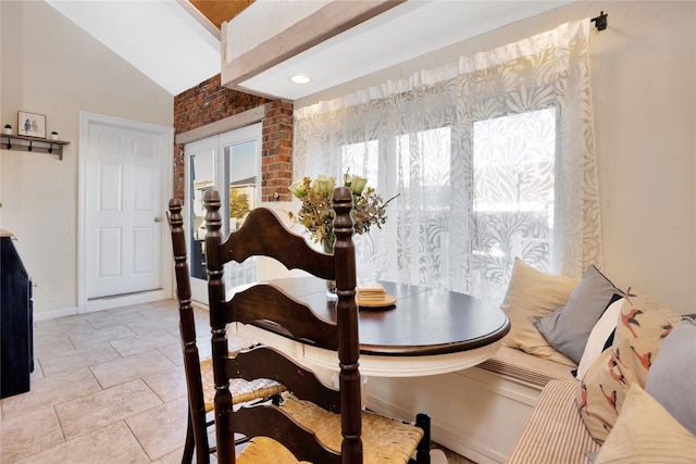 dining area with breakfast area, brick wall, and vaulted ceiling