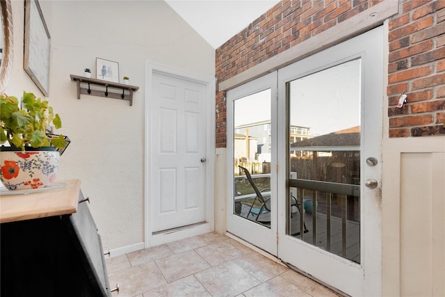 doorway to outside with brick wall and vaulted ceiling