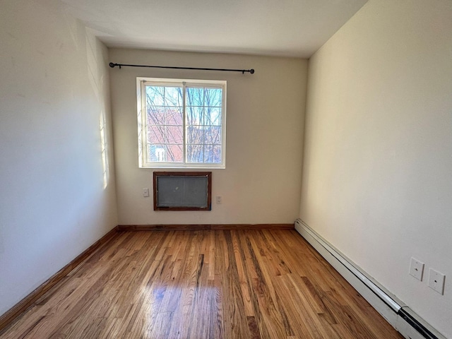 unfurnished room with baseboard heating and light hardwood / wood-style floors