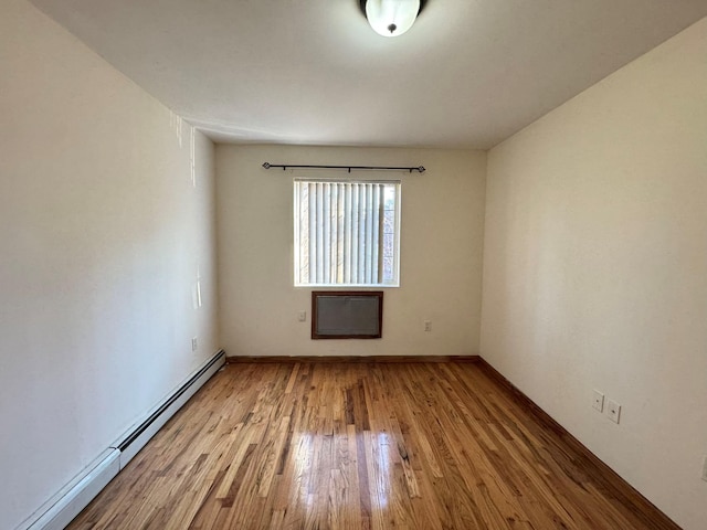 empty room featuring hardwood / wood-style floors and baseboard heating