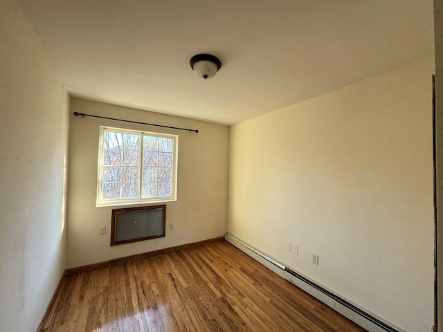 empty room with hardwood / wood-style floors and a baseboard heating unit