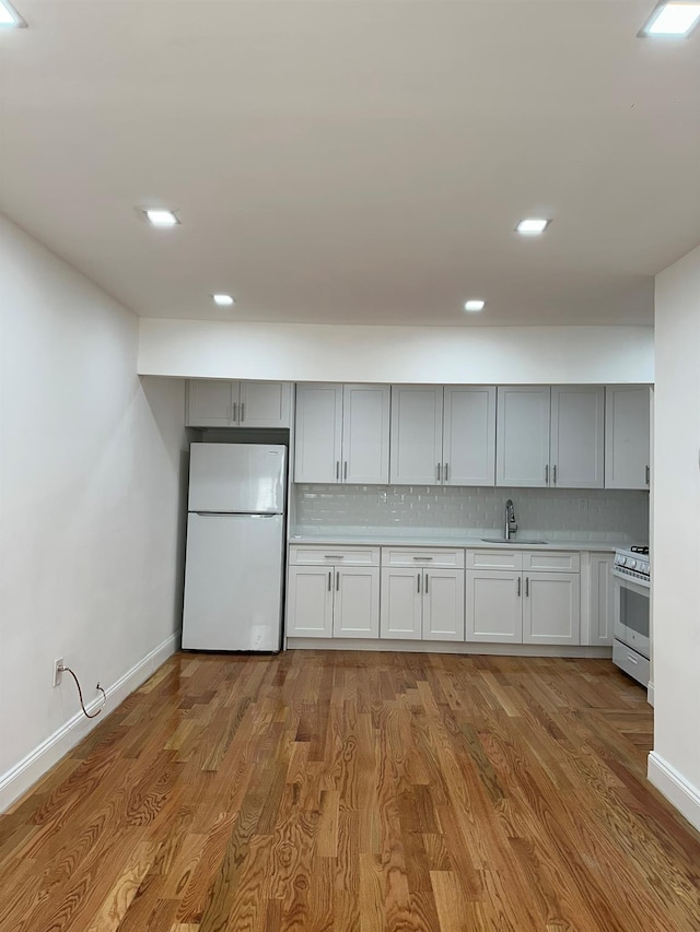 kitchen featuring sink, white fridge, light hardwood / wood-style floors, and stainless steel range oven