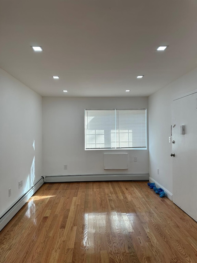 unfurnished room featuring light hardwood / wood-style floors and a baseboard radiator