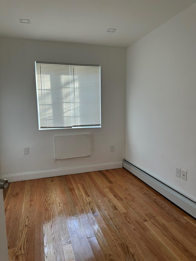 empty room with light hardwood / wood-style flooring and a baseboard radiator