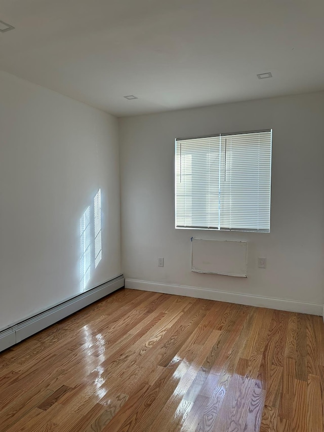 spare room featuring a baseboard radiator and light wood-type flooring