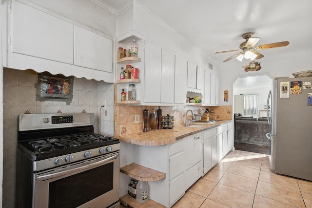 kitchen featuring backsplash, white cabinets, sink, light tile patterned floors, and stainless steel appliances