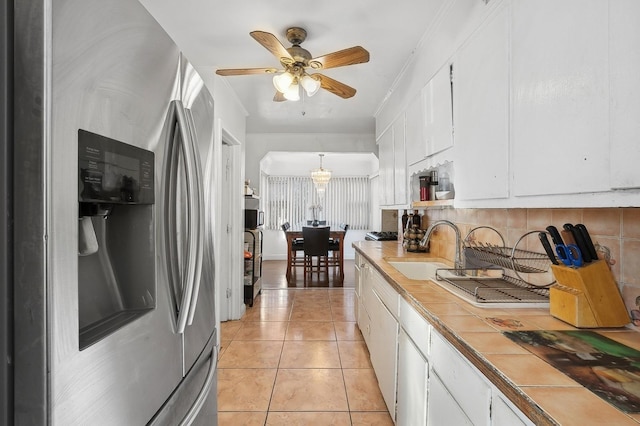 kitchen with sink, decorative backsplash, stainless steel fridge, decorative light fixtures, and white cabinetry