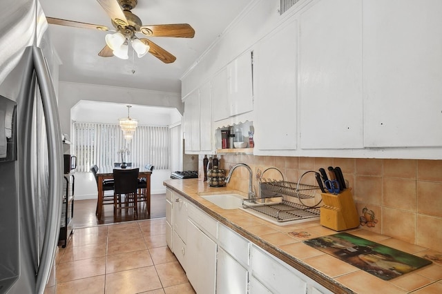 kitchen with stainless steel fridge, tasteful backsplash, pendant lighting, white cabinets, and tile counters