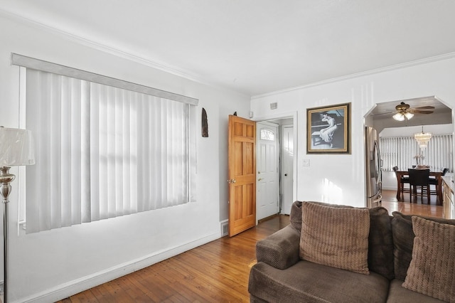 living room featuring hardwood / wood-style floors, ceiling fan, and crown molding