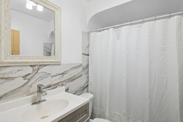 bathroom with vanity, backsplash, toilet, and tile walls