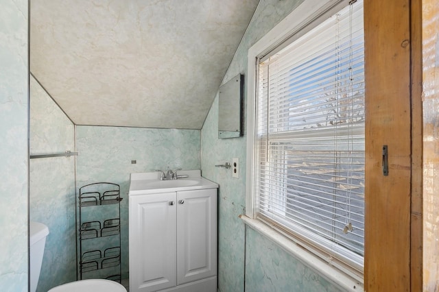 bathroom with vanity, toilet, and lofted ceiling