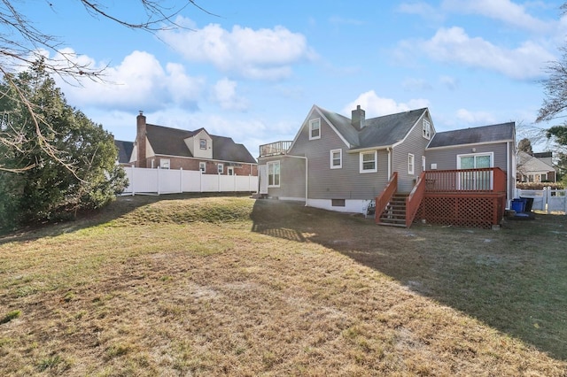 back of property featuring a wooden deck and a lawn