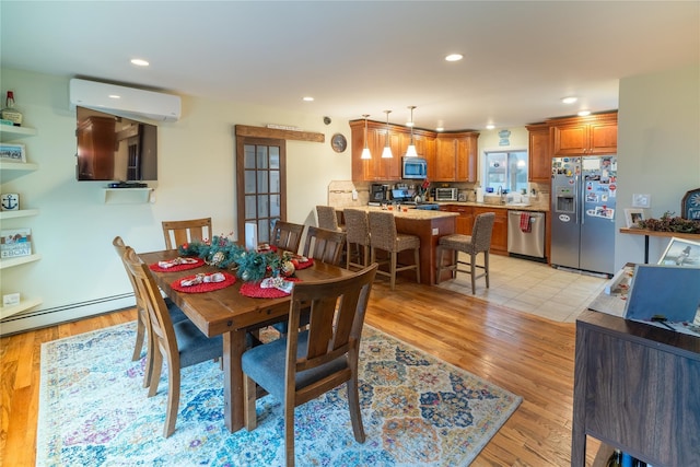 dining area with a baseboard radiator, a wall mounted air conditioner, and light wood-type flooring