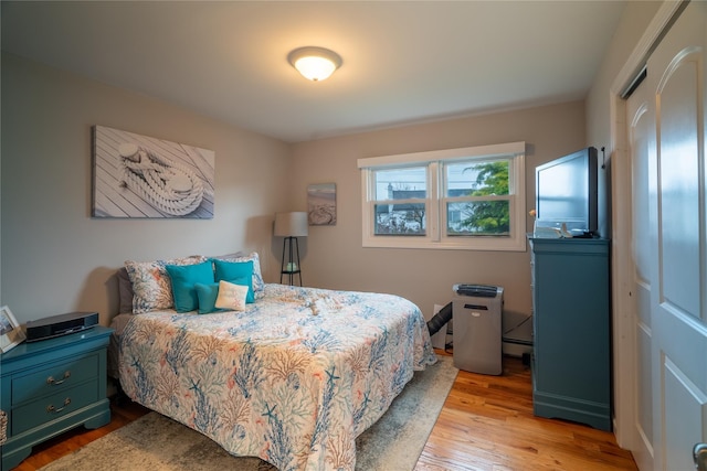 bedroom featuring light wood-type flooring and a baseboard heating unit