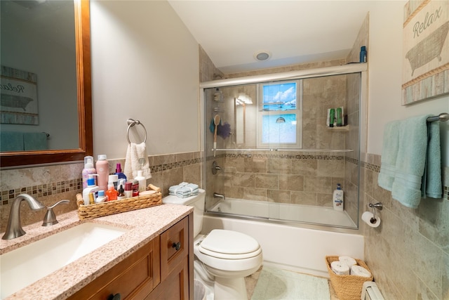 full bathroom featuring vanity, enclosed tub / shower combo, tile walls, and toilet