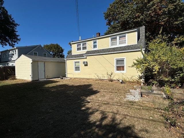 rear view of property with a yard and a storage unit