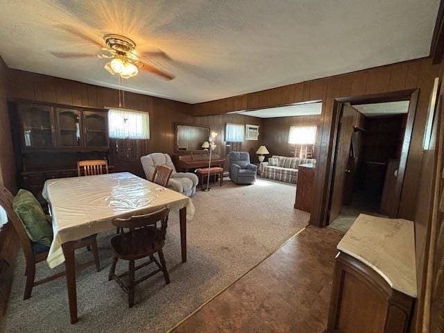 carpeted dining space with ceiling fan and wooden walls