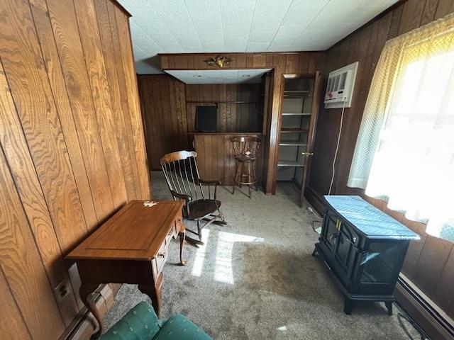 living area featuring plenty of natural light, wood walls, light colored carpet, and a wall mounted AC