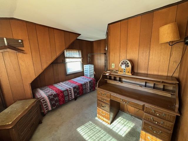 bedroom featuring light colored carpet, vaulted ceiling, and wood walls