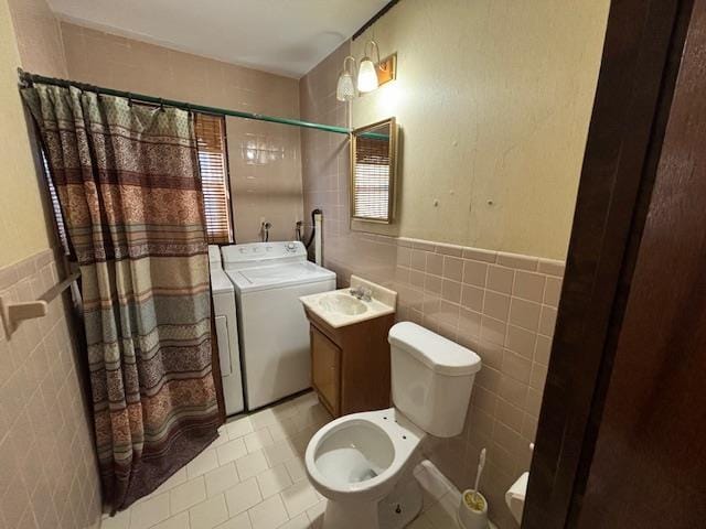 bathroom featuring vanity, tile patterned floors, toilet, tile walls, and washer / clothes dryer