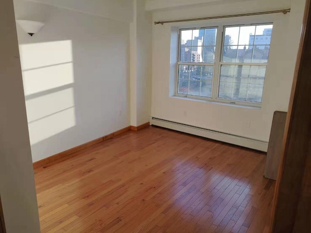 empty room with light hardwood / wood-style flooring and a baseboard heating unit