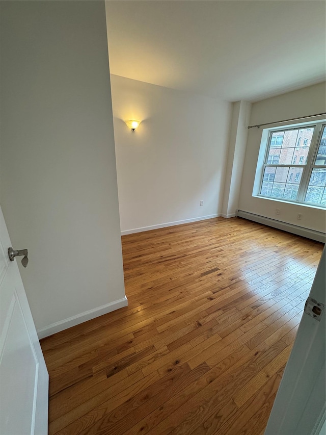 empty room featuring baseboard heating and light hardwood / wood-style floors