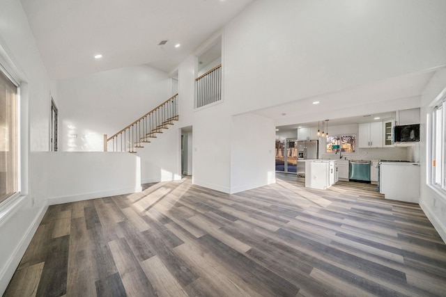 unfurnished living room featuring hardwood / wood-style floors and a towering ceiling