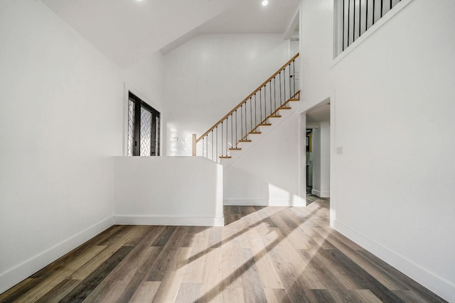 interior space with a towering ceiling and dark wood-type flooring