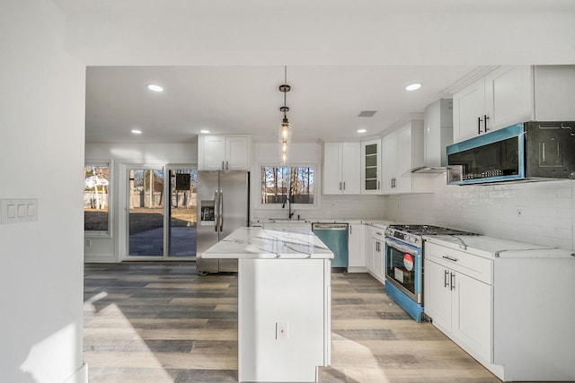 kitchen with wall chimney exhaust hood, white cabinetry, and appliances with stainless steel finishes