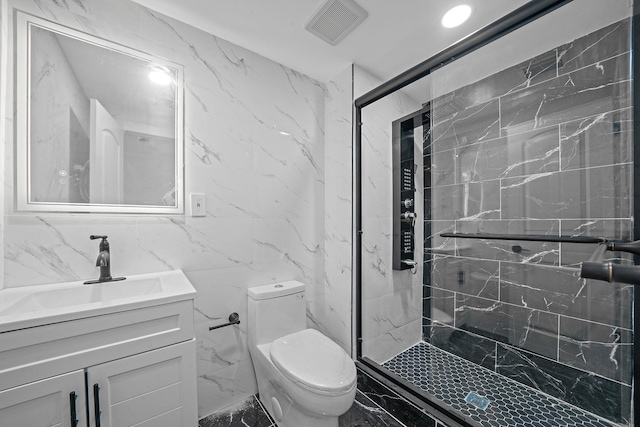 bathroom with vanity, a shower with door, toilet, and tile walls