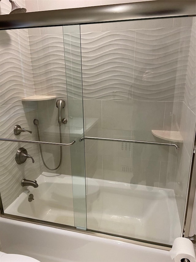 bathroom with toilet and combined bath / shower with glass door