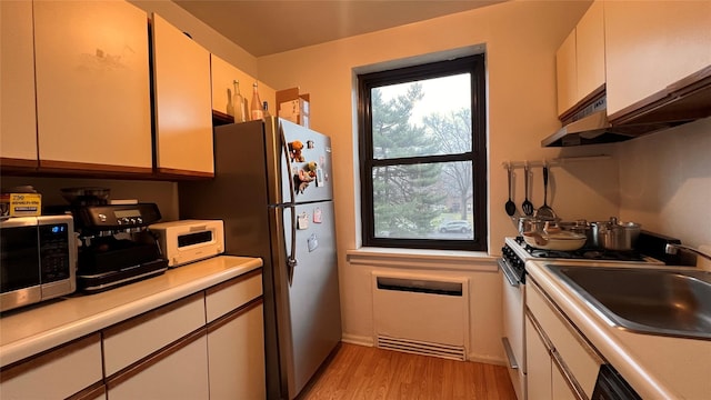 kitchen featuring stainless steel appliances, white cabinets, and light hardwood / wood-style floors