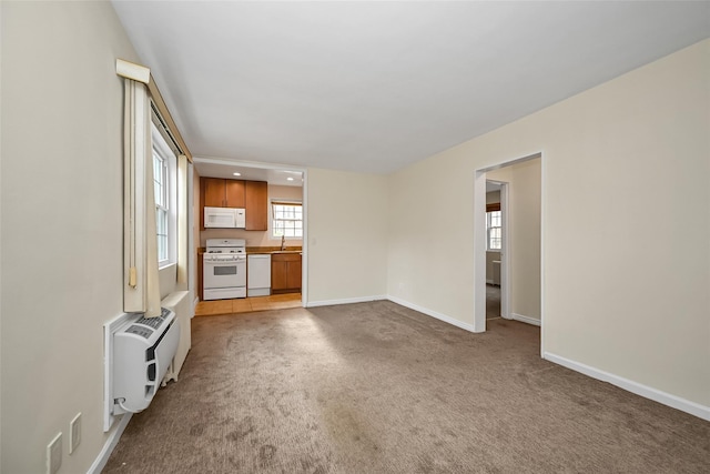 unfurnished living room featuring recessed lighting, light carpet, a sink, and baseboards