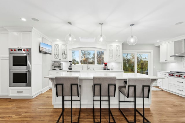 kitchen with white cabinets, stainless steel appliances, a kitchen island, and tasteful backsplash